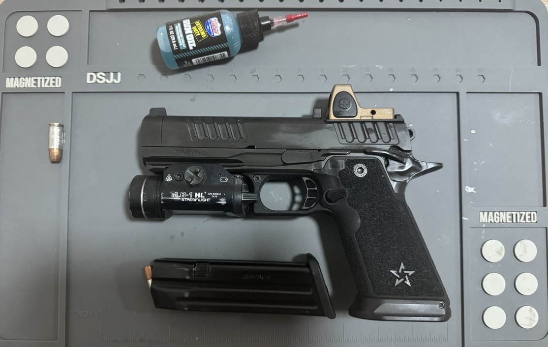 Staccato HD 4.5 duty pistol with optic, weapon light, and magazine on a workbench
